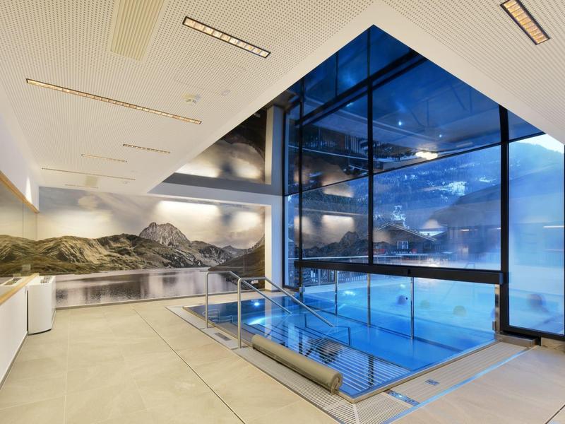 Moderner Innenpool mit Glasumrandung, großen Fenstern und Berglandschaft-Wandbild.