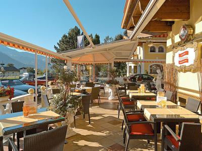 Sonnige Außenbereich-Terrasse eines Hotels mit gedeckten Tischen und Blick auf Berge.