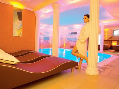 Ein entspannter Wellnessbereich mit Liegen, Pool und warmem, farbigem Licht.