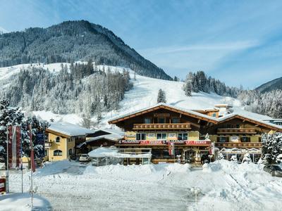 Großes Berghotel im Winter mit Schnee bedecktem Gelände und umgeben von Bergen.