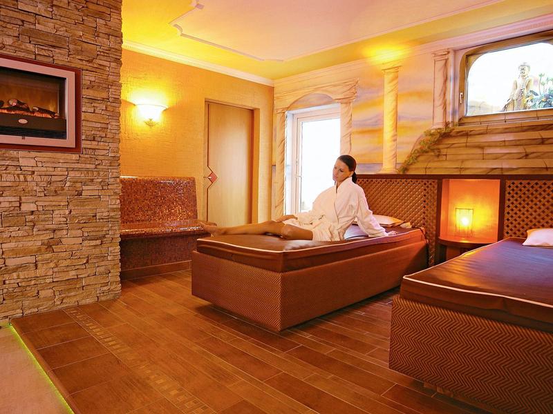 Ein gemütlicher Raum mit zwei Betten, warmem Licht und einer Person in weißem Bademantel.