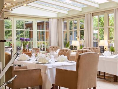 Elegantes Restaurant mit weiß gedeckten Tischen und großen Fenstern mit Blick ins Grüne.