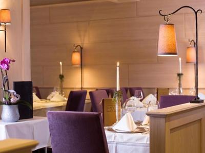 Elegantes Restaurant mit gedeckten Tischen, violetten Sesseln und warmem Licht.