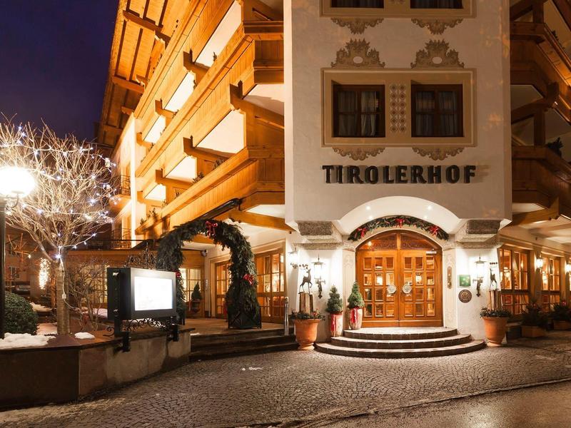 Beleuchtetes Hotelgebäude mit Balkon, Holzverkleidung und schneebedecktem Gehweg bei Nacht.