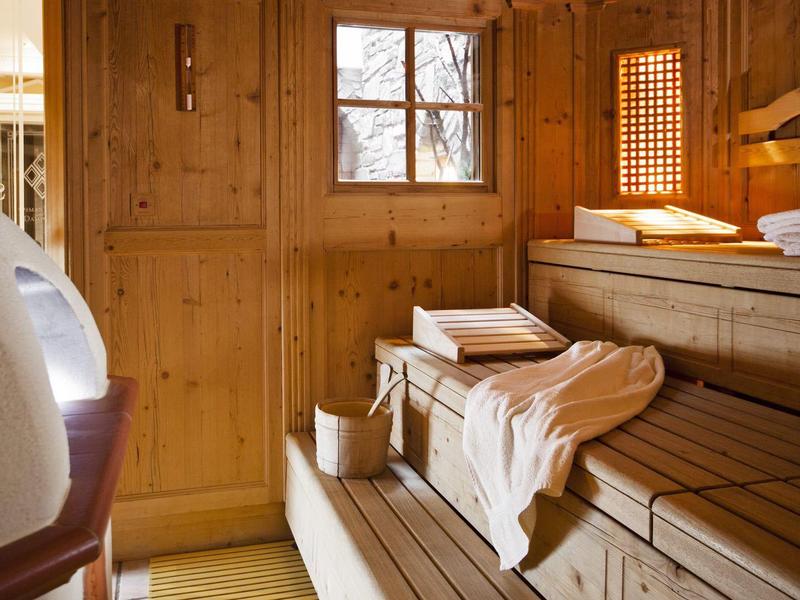 Holzsauna mit mehrstufigen Bänken, Handtüchern, einem Fenster und gedämpftem Licht.