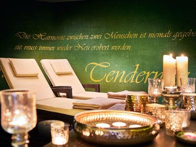 Gemütliche Spa-Szene mit bequemen Liegestühlen, Kerzen und goldenem Dekor in warmem Licht.