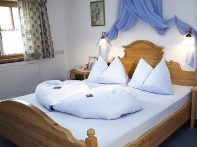 Hell eingerichtetes Schlafzimmer mit Holzbett, weißen Bettdecken und blauer Wanddekoration.