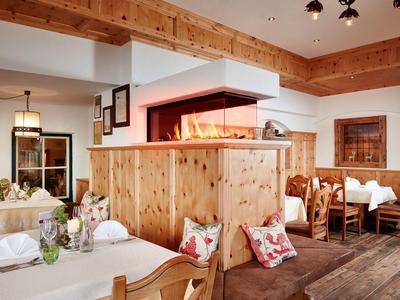 Gemütlicher Restaurantbereich mit Holzmöbeln, Kamin und dekorativen Kissen