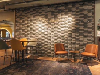 Gemütlicher Hotel-Loungebereich mit Sessel, Tischen und gemusterter Wand.