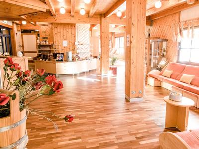 Heller Hotel-Lobby mit Holzbalken, Sitzbereich, Blumen und warmem Licht.