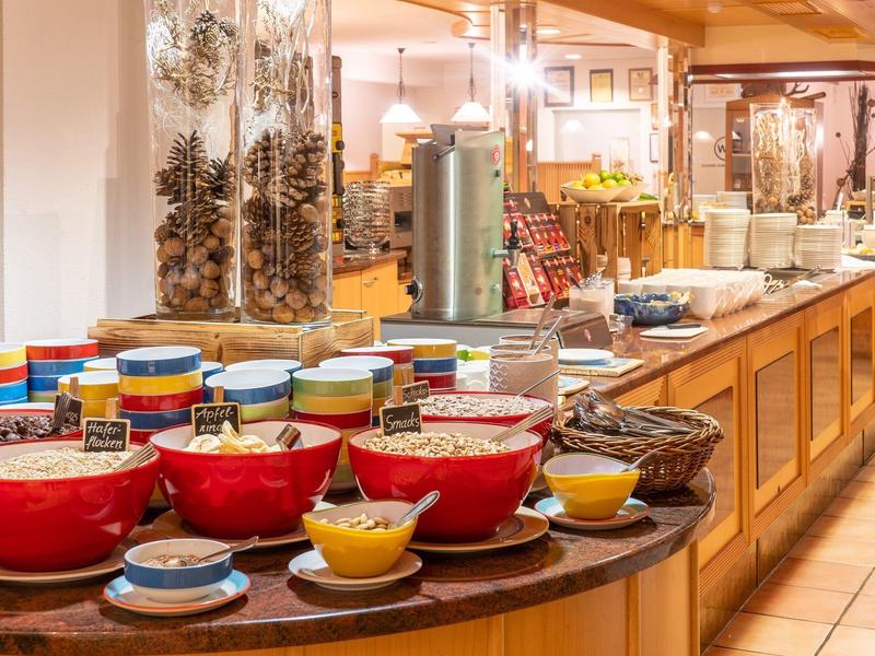 Buffet mit verschiedenen Schalen, Bechern und Dekoration aus Kiefernzapfen auf Holztheke.