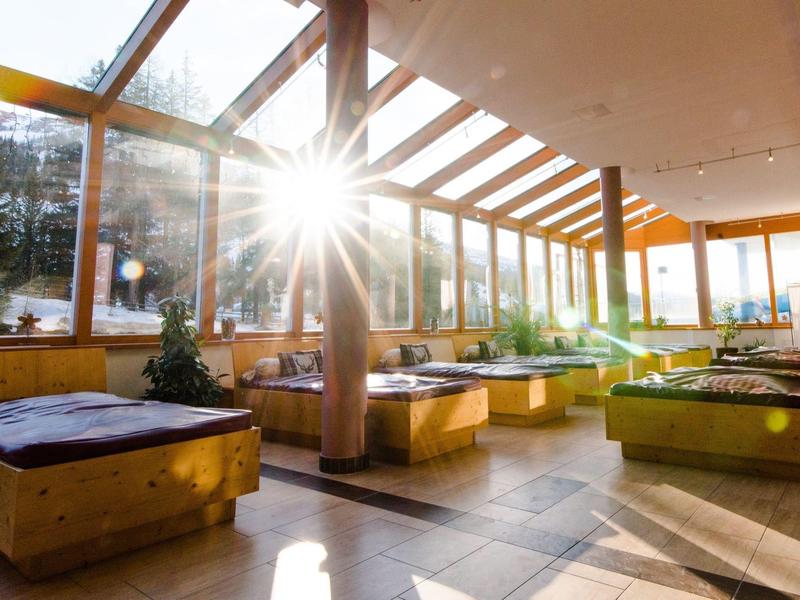 Sonnenlicht strahlt durch große Fenster in einen gemütlichen Ruheraum mit Holzmöbeln in einem Hotel.