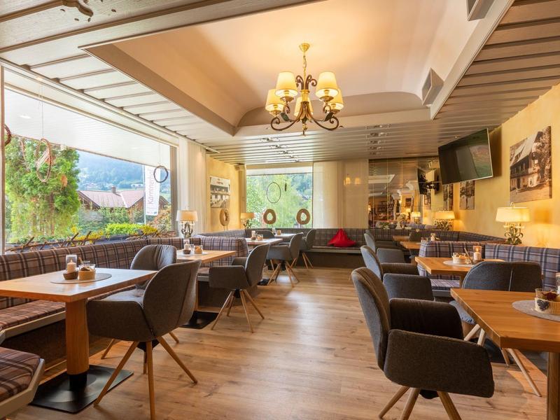 Gemütliches Restaurant mit Holzboden, grauen Stühlen, Holztischen und großer Fensterfront.