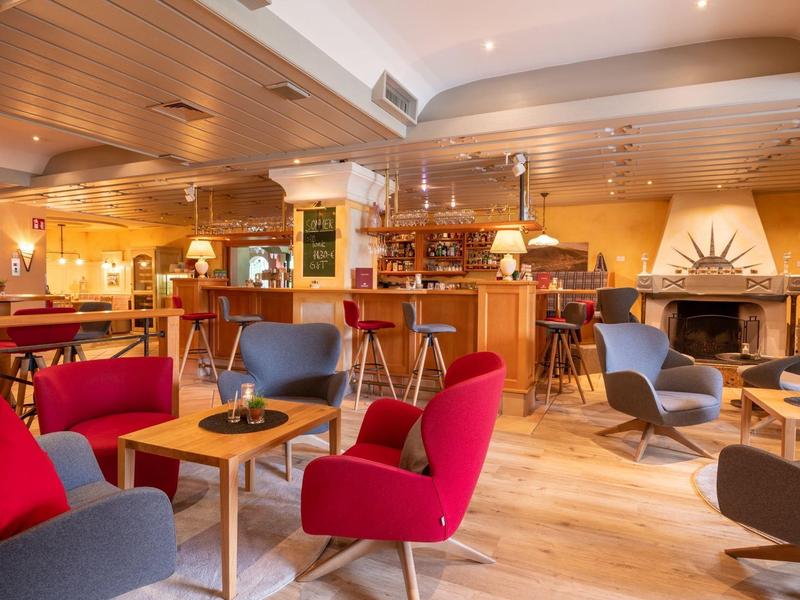 Gemütliche Hotelbar mit bunten Sesseln, Holzmo?beln und Kamin in warmem, hellem Ambiente.