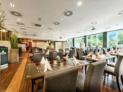 Helles, modernes Restaurant mit Holzboden und großen Fenstern mit Bergblick.