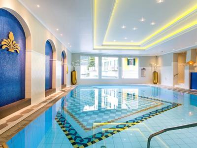 Innenpool mit blauem Wasser, dekorativen Wänden und indirekter Beleuchtung an der Decke.