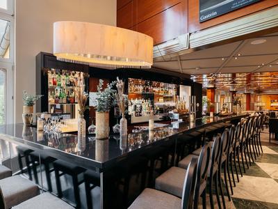 Moderner Hotelbarbereich mit stilvollen Stühlen und indirekter Beleuchtung.