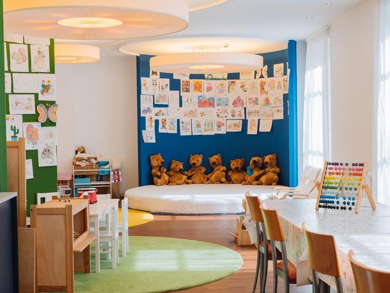 Ein heller, freundlicher Klassenraum mit Teddybären, Kinderzeichnungen und buntem Spielzeug.