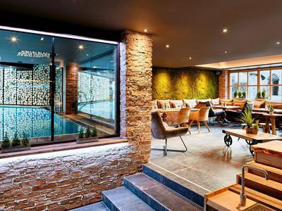 Modern hotel interior with lounge, seating, and illuminated window to spa or pool area.