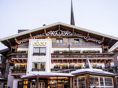 Hôtel alpin traditionnel avec balcons et décorations en bois dans un cadre hivernal enneigé.