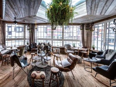 Cozy lounge with wooden floor, various seating groups, and large windows