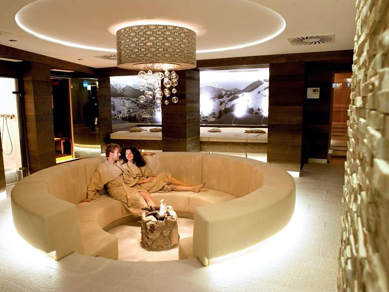 Salon d'hôtel élégant avec canapé beige rond, lumière de plafond moderne et œuvres d'art aux murs.