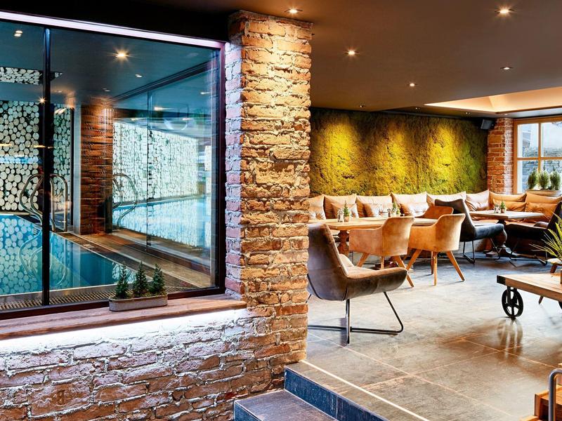 Espace lounge moderne avec fauteuils confortables, escalier en pierre et mur végétal en arrière-plan.