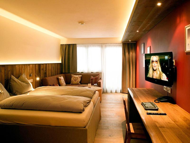 Chambre d'hôtel confortable avec lit double, boiseries et télévision sur mur rouge.