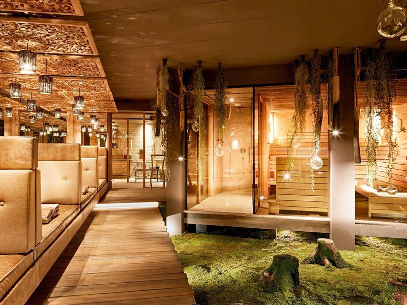 Intérieur élégant avec sol en bois, bancs rembourrés et végétation apaisante.