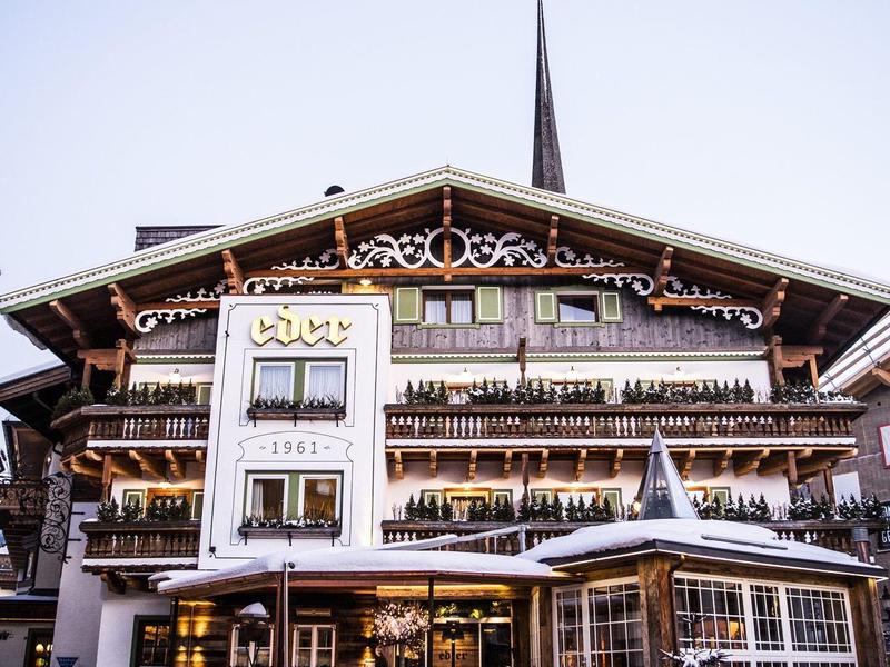 Hôtel alpin traditionnel avec balcons et décorations en bois dans un cadre hivernal enneigé.