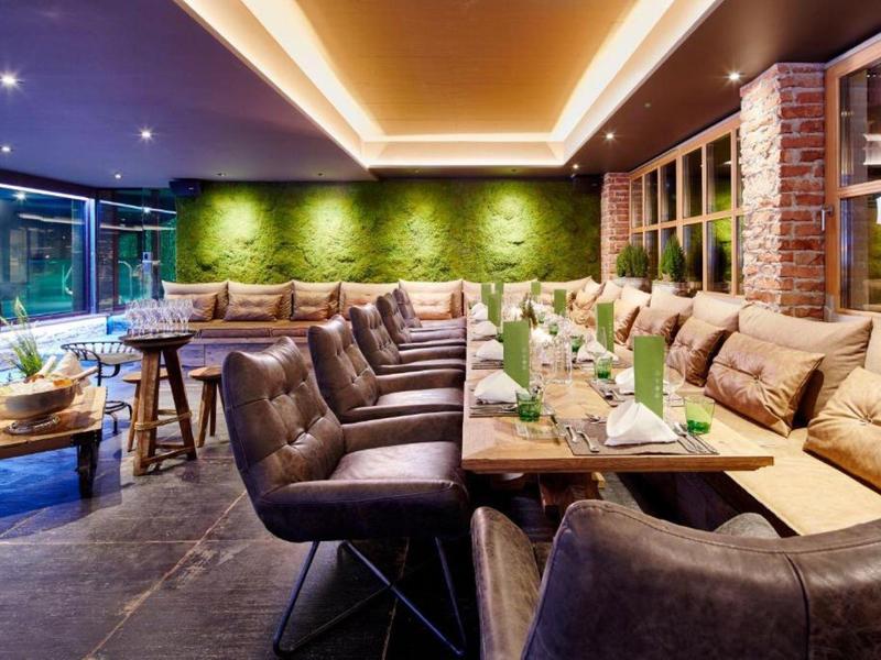 Espace de travail d'hôtel élégant avec grandes tables, chaises confortables et décor végétal.