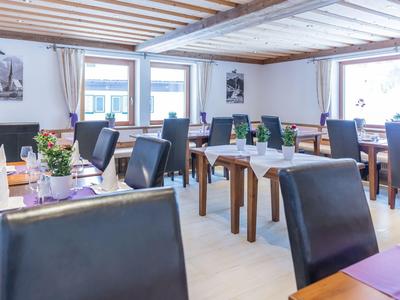 Ristorante luminoso con tavoli, sedie nere e piante decorative sui tavoli.