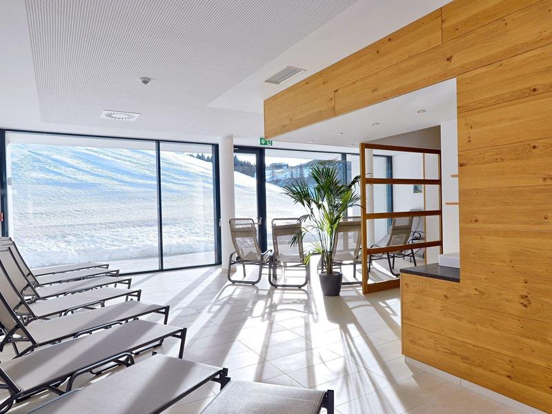 Moderní odpočinková místnost s lehátky a velkými okny s výhledem na hory.