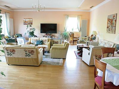 Lichte, gezellige hotelwoonruimte met banken, fauteuils, planten en een tv.