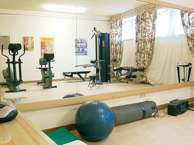 Goed verlichte fitnessruimte met trainingsapparatuur en spiegelwand.