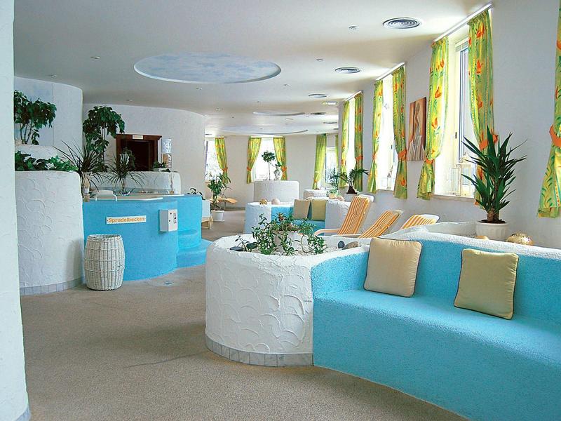 Lichte hotel lobby met blauwe banken en grote ramen met gordijnen.