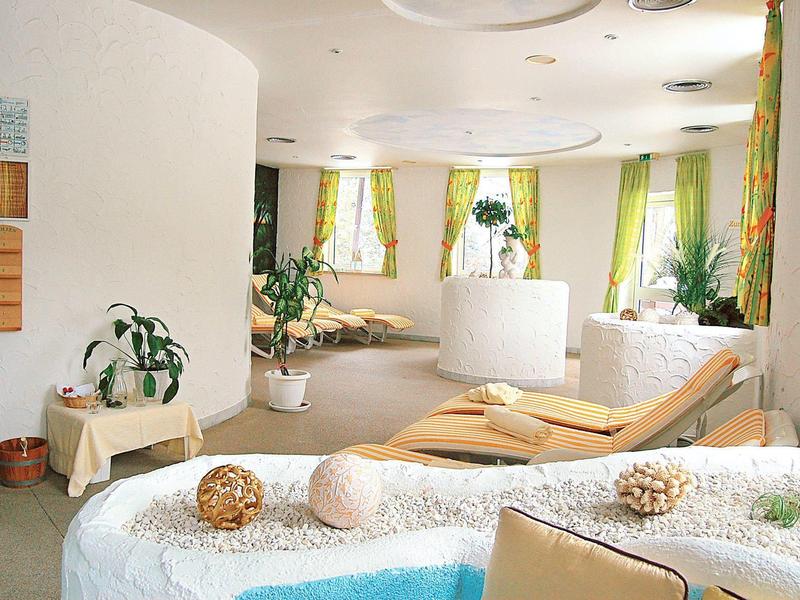 Lichte wellness/lounge met ligstoelen, planten en zachte kleuren voor ontspanning.