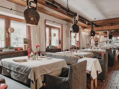 Restaurante rústico con mesas preparadas y grandes campanas colgando del techo.