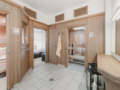 Bright spa area with wood paneling, changing room, and view into sauna and adjoining room.