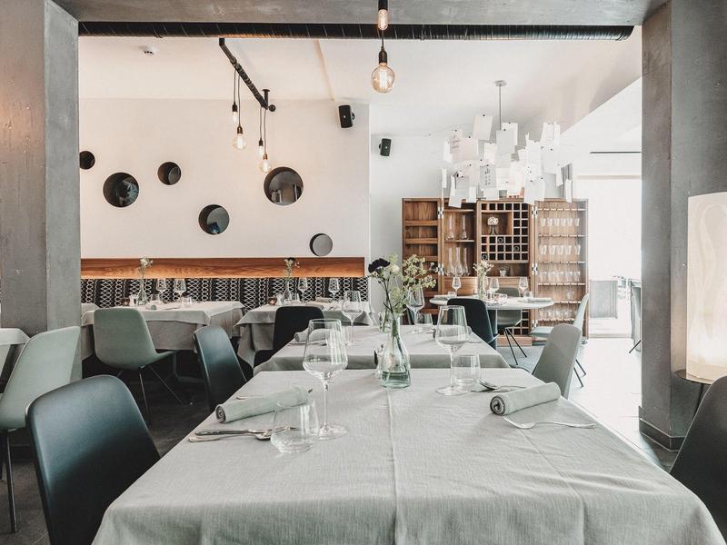 Modern restaurant with set tables, chairs, and decorative wall objects in a bright atmosphere.