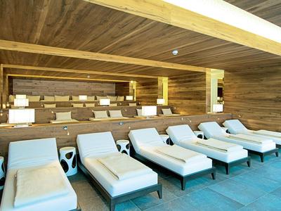 Wygodne leżaki z poduszkami przed drewnianą ścianą w strefie spa.