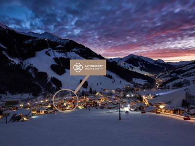 Widok na zaśnieżoną górską wioskę o zachodzie słońca z oświetlonymi domami i górami