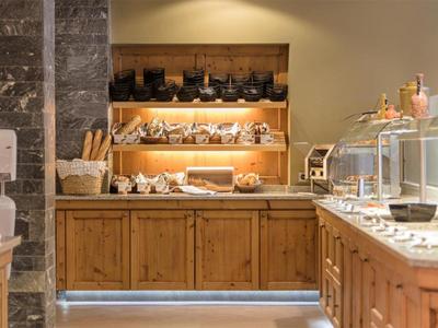 Strefa bufetu z drewnianymi meblami i wyborem chleba oraz produktów śniadaniowych.