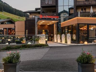 Modernes Hotel mit großer Glasfassade und gut beleuchtetem Eingangsbereich in Bergumgebung.