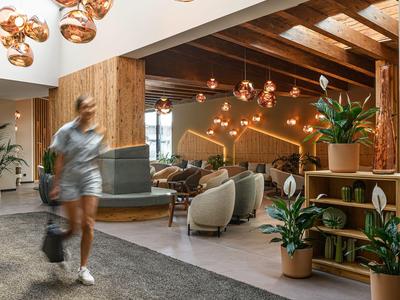 Modernes Hotel-Lounge mit Holzdecke, Kupferlampen und gemütlichen Sitzbereichen.