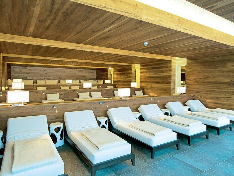 Wygodne leżaki z poduszkami przed drewnianą ścianą w strefie spa.