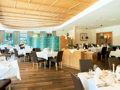 Světelná restaurace s dřevěným stropem, bílými ubrusy a elegantní výzdobou stolů.