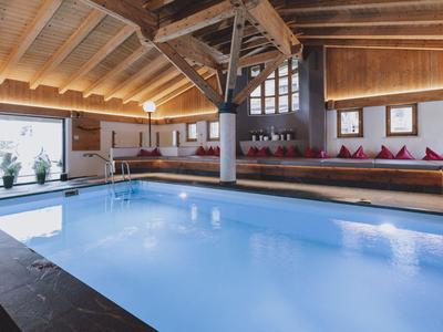 Piscina interior en una habitación de madera con zonas de asientos acogedoras y grandes ventanas