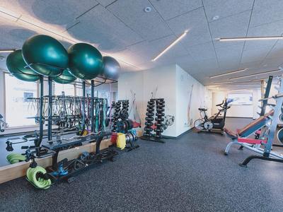 Gimnasio luminoso con varios equipos de entrenamiento y grandes ventanas