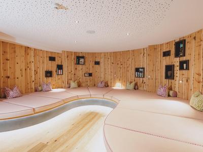 Pohodlná relaxační místnost ve spa s zakřiveným dřevěným interiérem a měkkými polštáři na sezení.